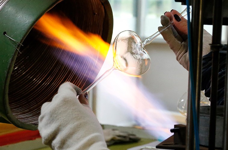 Glasbläser in der Manufaktur von Inge Glas formt eine Christbaumkugel vor der Flamme – Handwerkskunst hinter mundgeblasenem Christbaumschmuck
