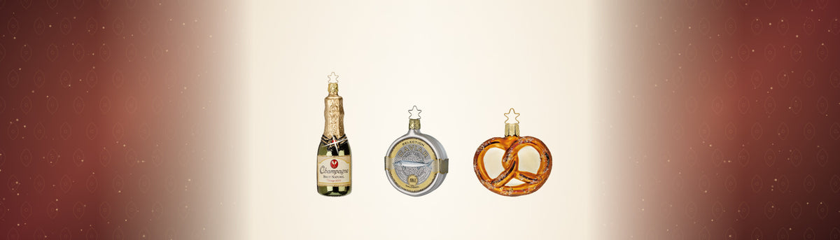 Champagnerflasche, Kaviardose und Laugenbrezel als Glasornamente von Inge-Glas vor bordeauxrotem Damast