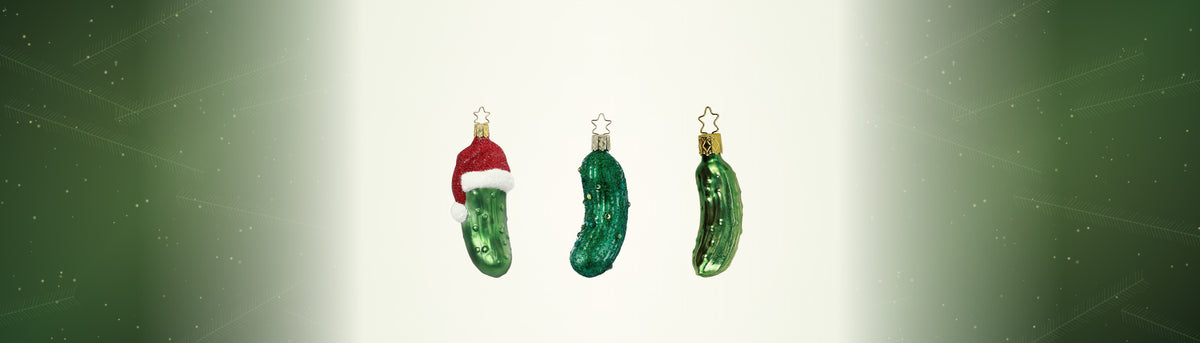 Drei Weihnachtsgurken aus Glas von Inge-Glas zwischen Tannenzweigen: mit Nikolausmütze, im Glitzerkleid und im Einmachglas