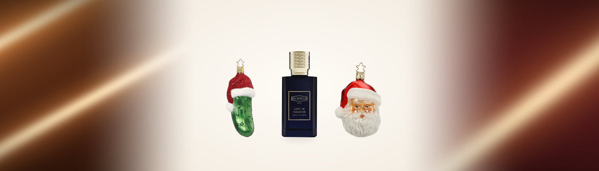 Weihnachtsgurke mit Nikolausmütze, Lust in Paradise von Ex Nihilo und ein gläserner Nikolaus auf hellem Grund zwischen kupferfarbener Seide
