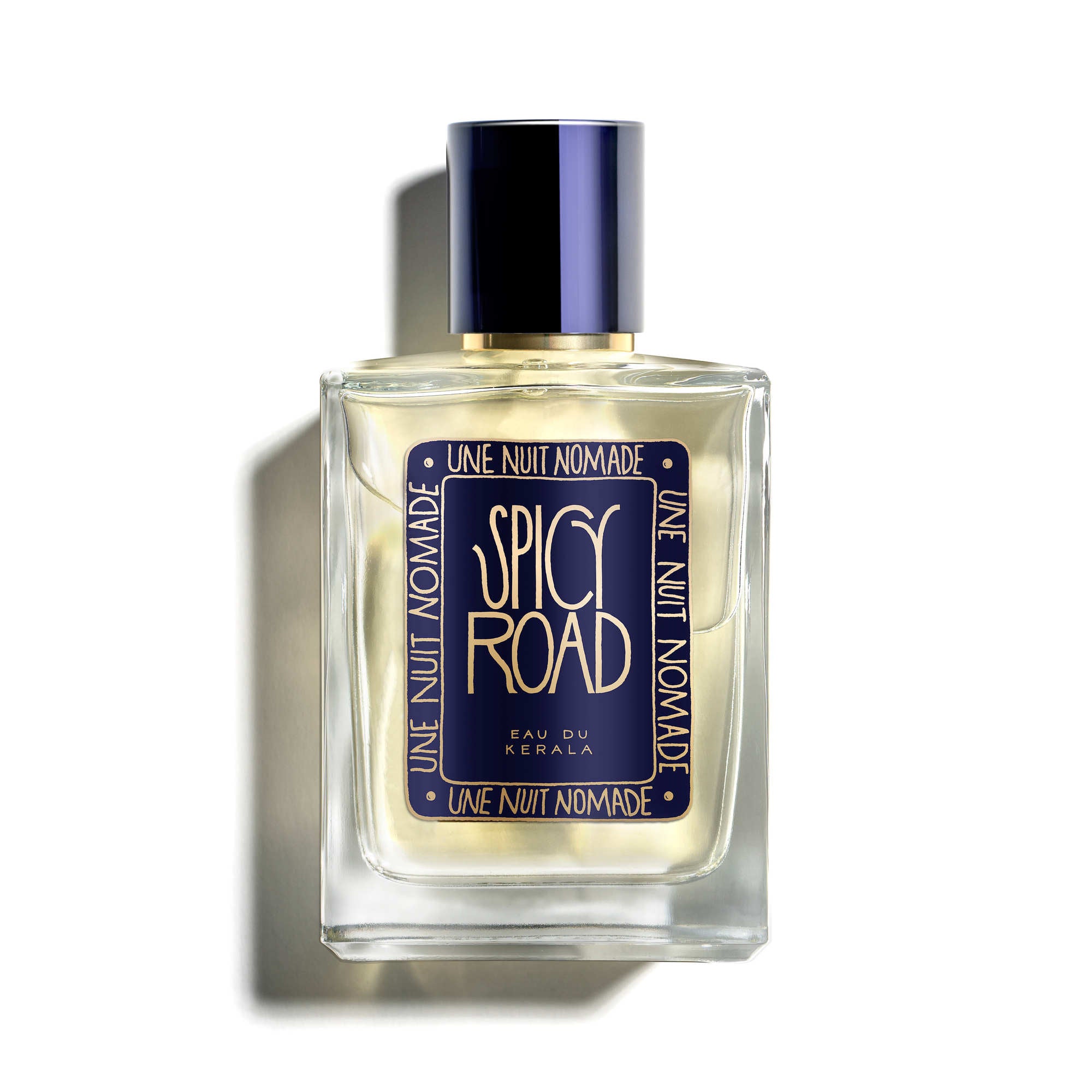 Une Nuit Nomade Spicy Road Eau de Parfum im klaren Glasflakon mit dunkelblauem Etikett, goldfarbener Schrift und dunkelblauem Zylinderdeckel.