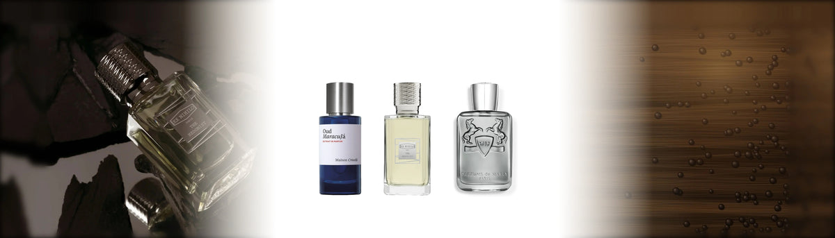 Oud Maracujá, The Hedonist und Castley auf weißem Grund zwischen dunklem Holz mit Pfefferkörnern und einem Ex-Nihilo-Flakon auf schwarzem Stein